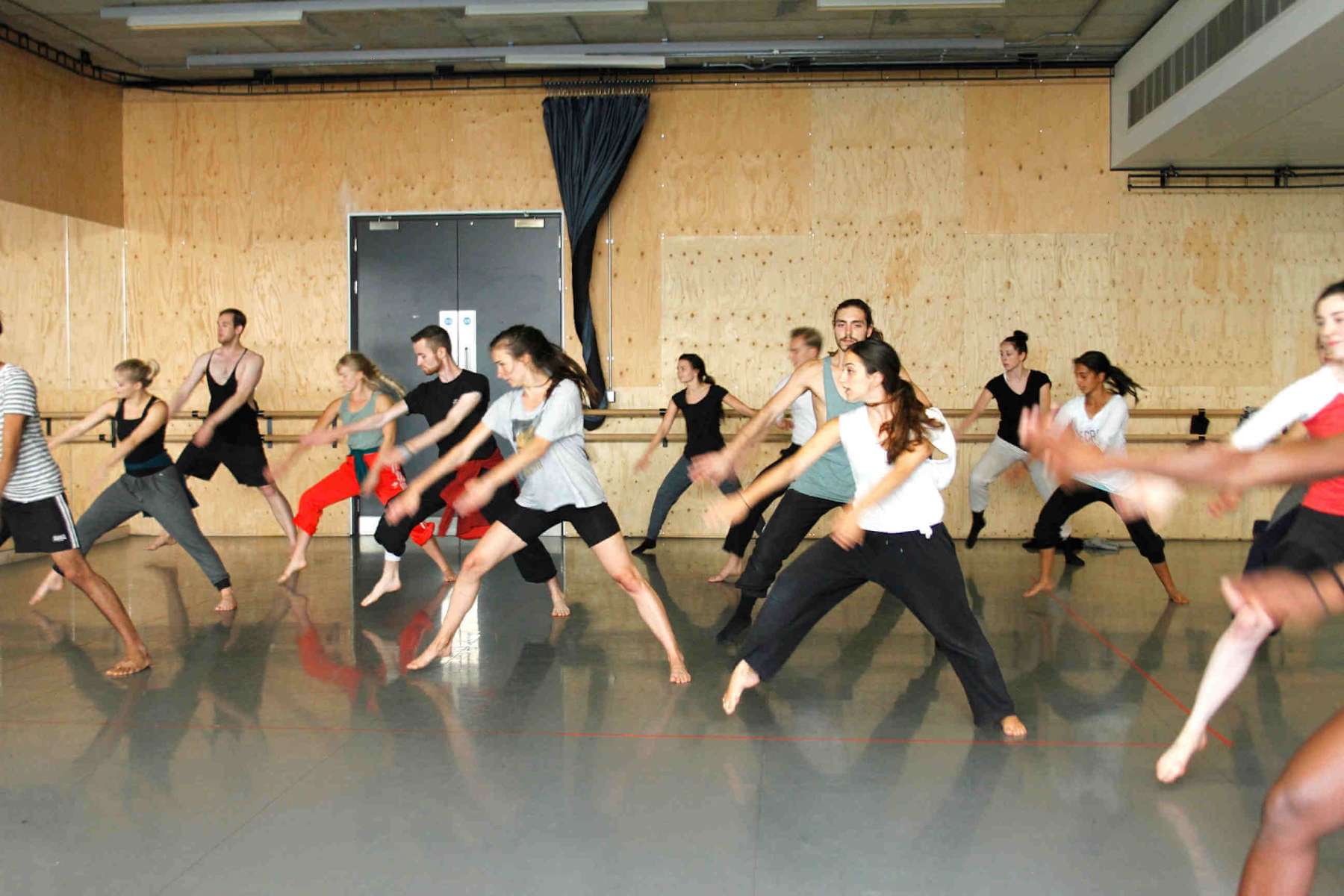 A group of dancers moving together in a studio
