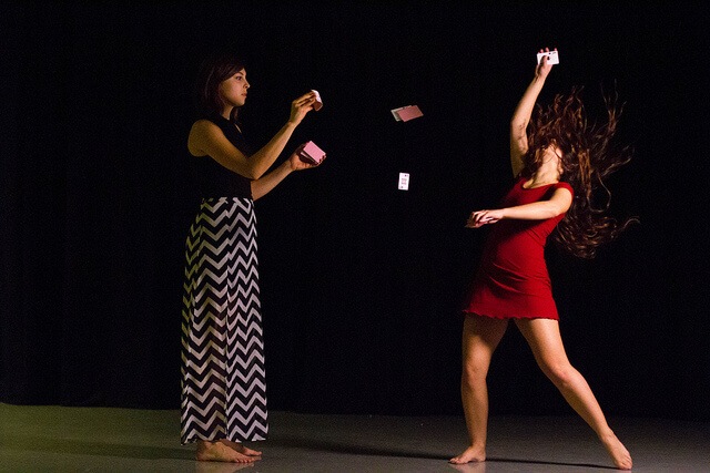 A woman flicks cards at vivian who is wearing a red dress